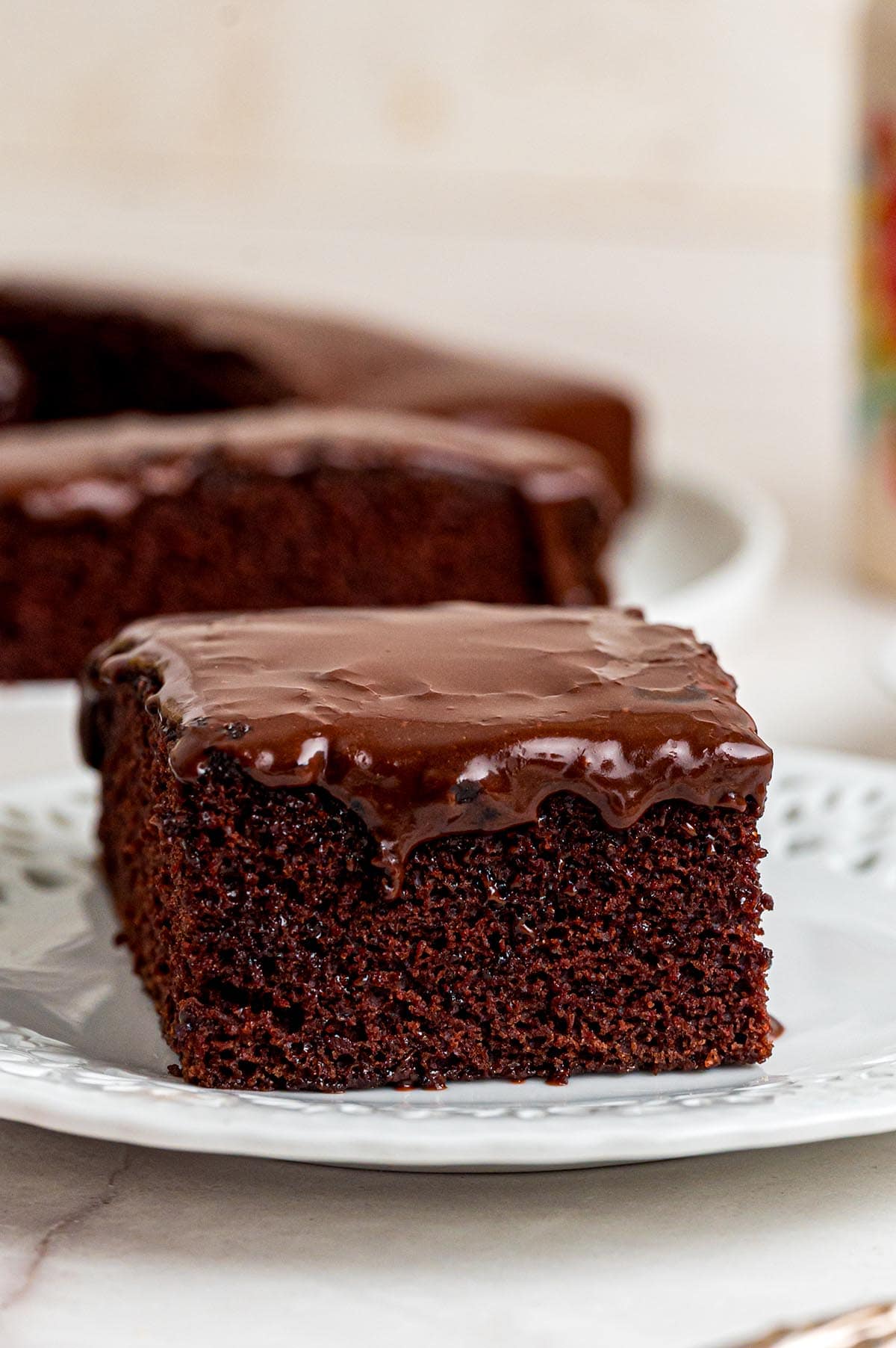 A moist slice of chocolate depression cake with a glossy chocolate frosting.