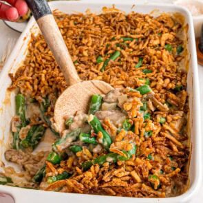 A creamy green bean casserole topped with crispy fried onions in a white baking dish.