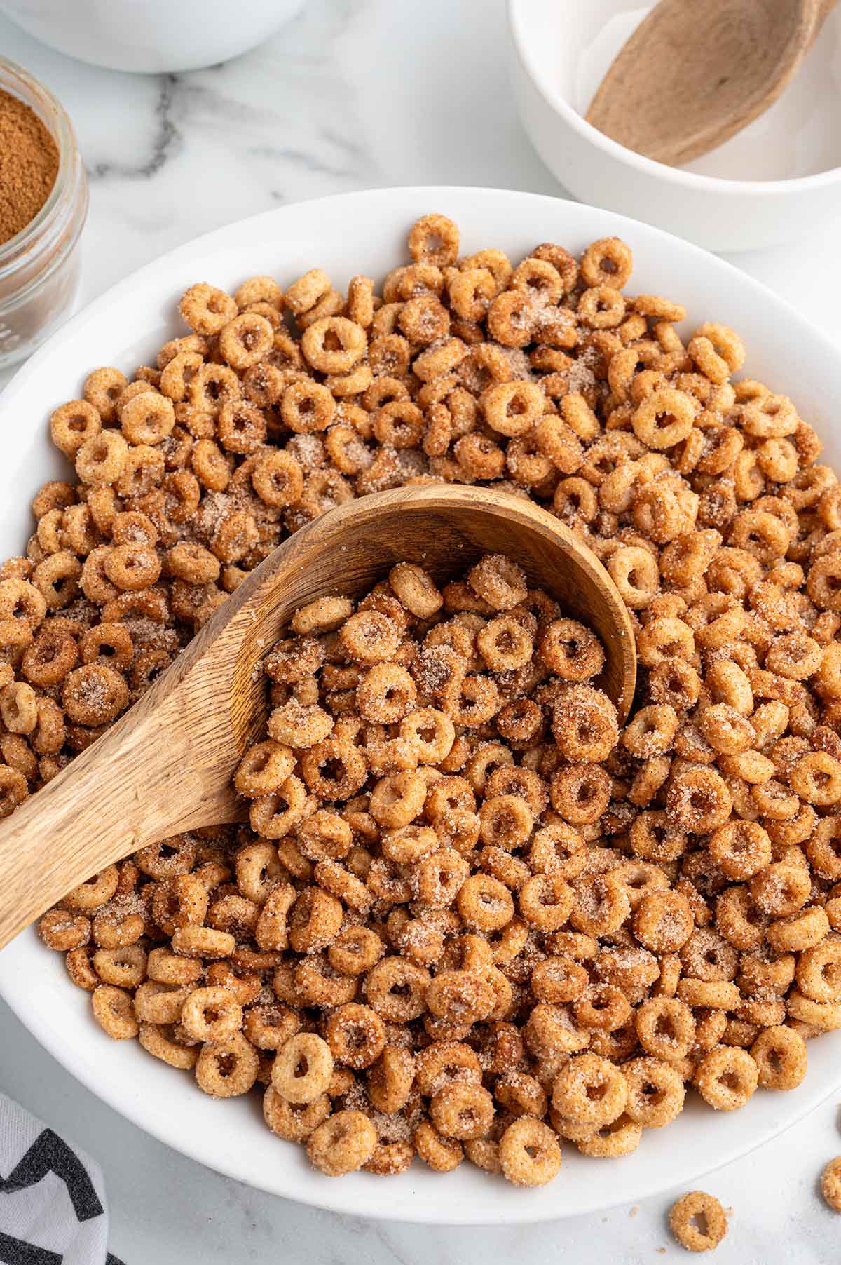 A bowl filled with mini donut-flavored Cheerios and a wooden spoon inside.