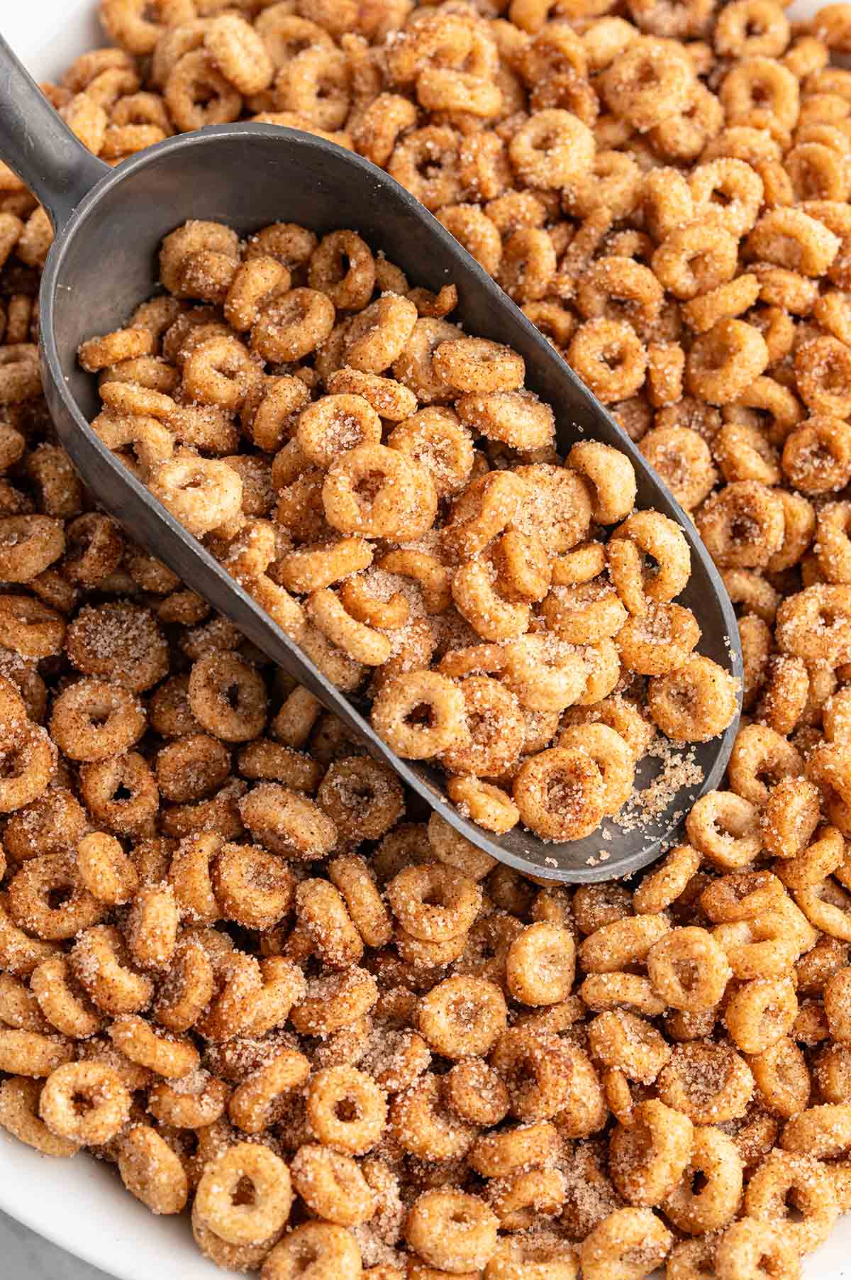 Mini donut-shaped Cheerios coated with cinnamon and sugar on a scoop.