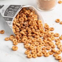 Mini donut-shaped hot buttered Cheerios spilling from a newspaper cone.