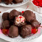 A plate full of Martha Washington candies covered in chocolate with a bite revealing cherry and coconut filling.