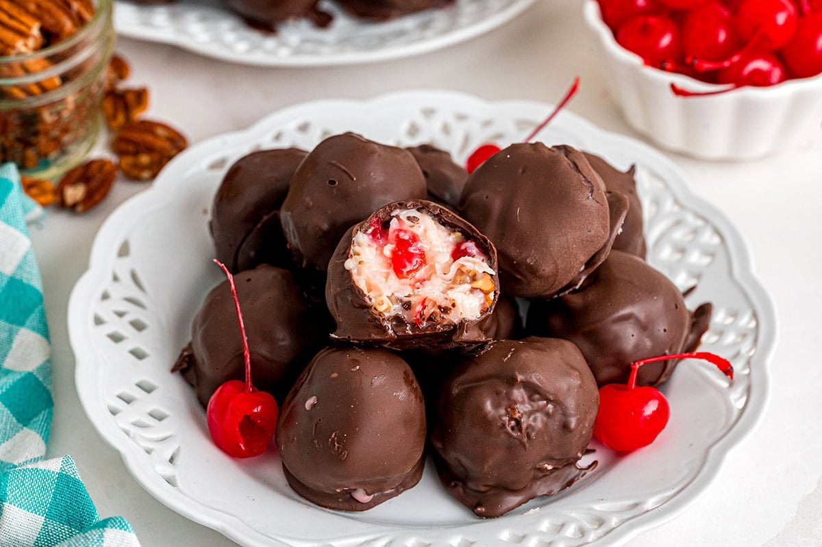 A plate of chocolate-covered Martha Washington candies with bright red cherries.