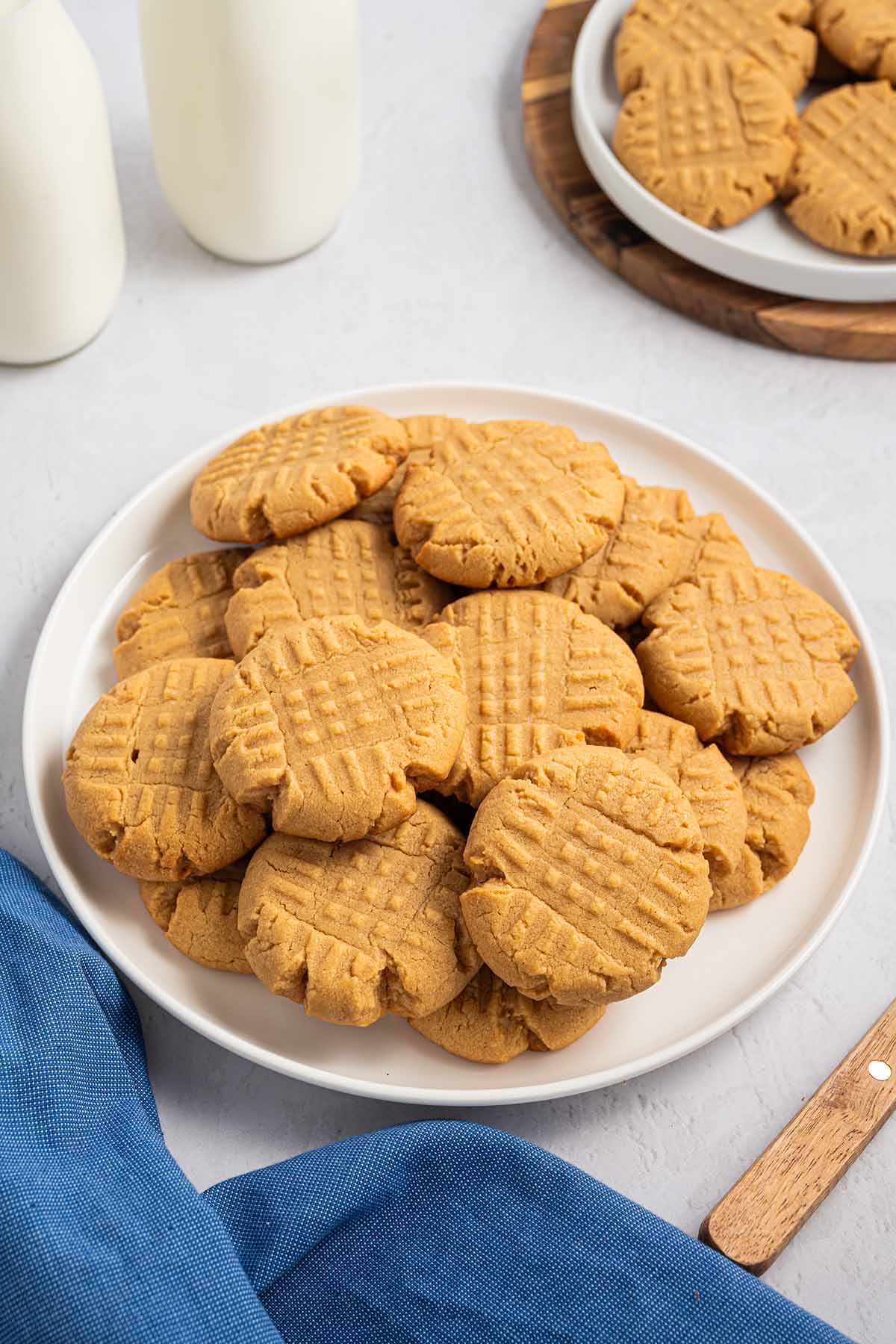 A plate full of golden cake mix peanut butter cookies with classic criss cross pattern and another plate in the background.