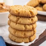 A stack of soft peanut butter cookies on parchment paper.