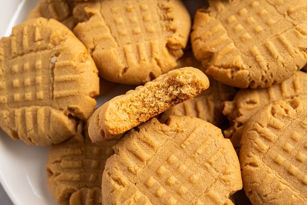 A plate full of soft cake mix peanut butter cookies, one with a bite taken out.