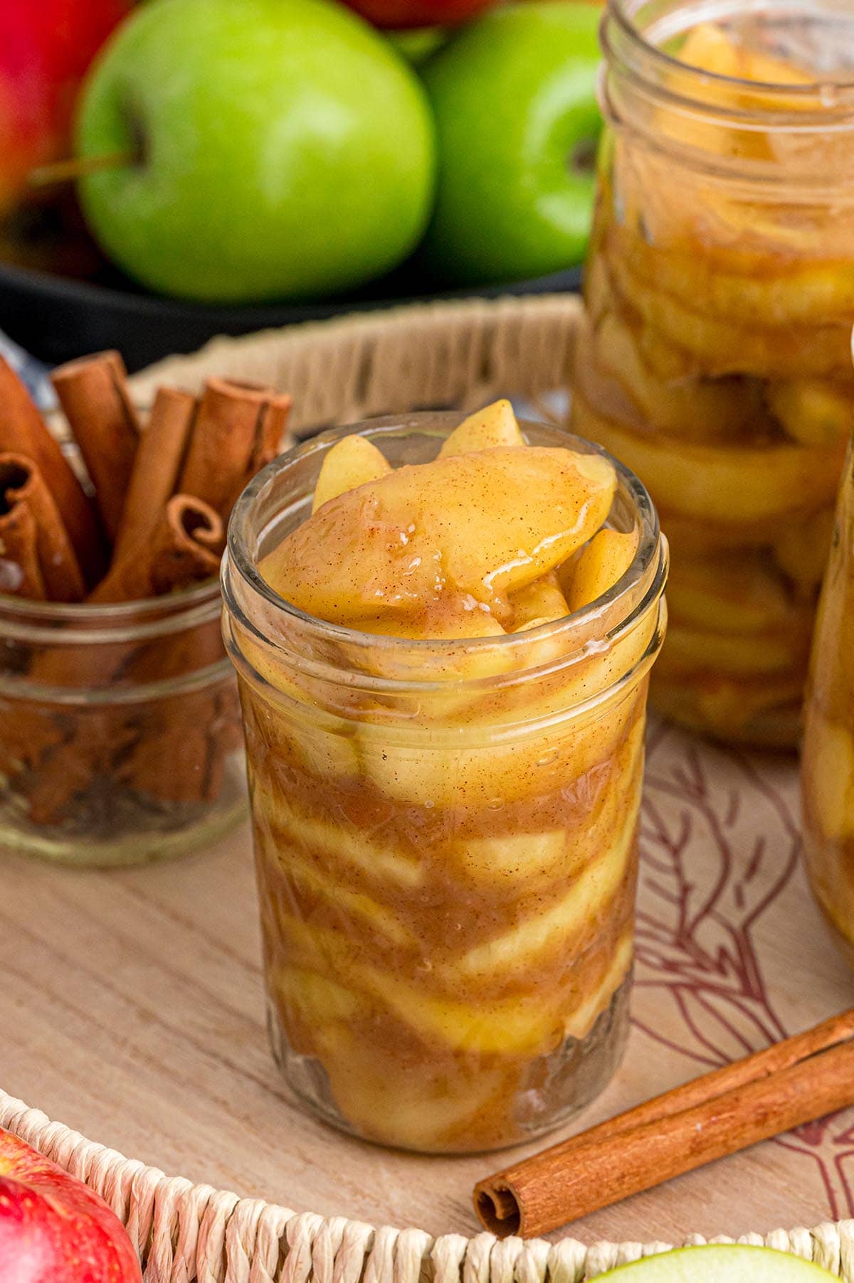 Apple pie filling made from slices of apples mixed with cinnamon inside a clear jar.