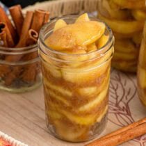 A jar filled with warm apple pie filling and cinnamon.