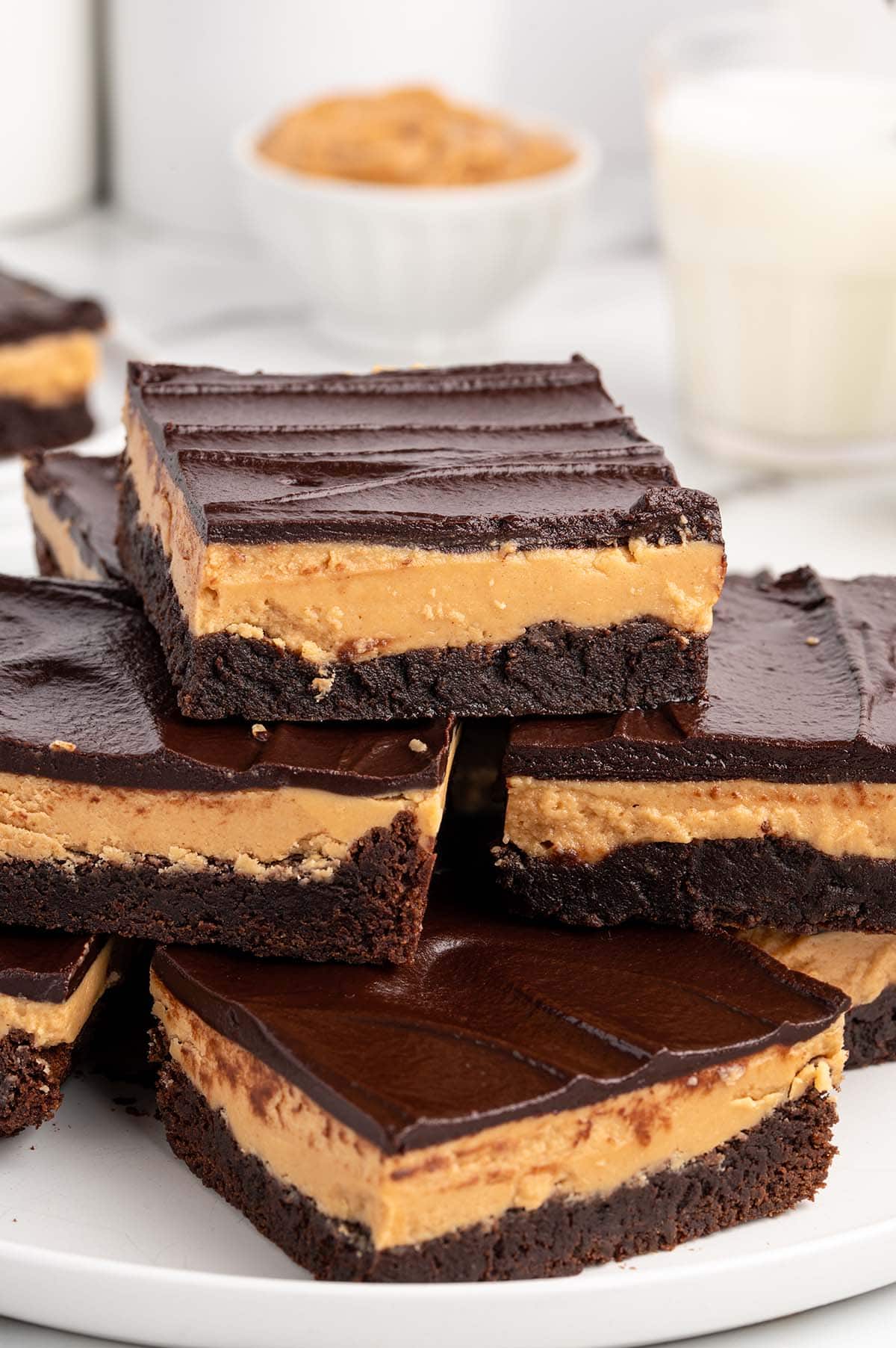 Stack of Buckeye brownies with peanut butter centers and chocolate tops on a white plate.