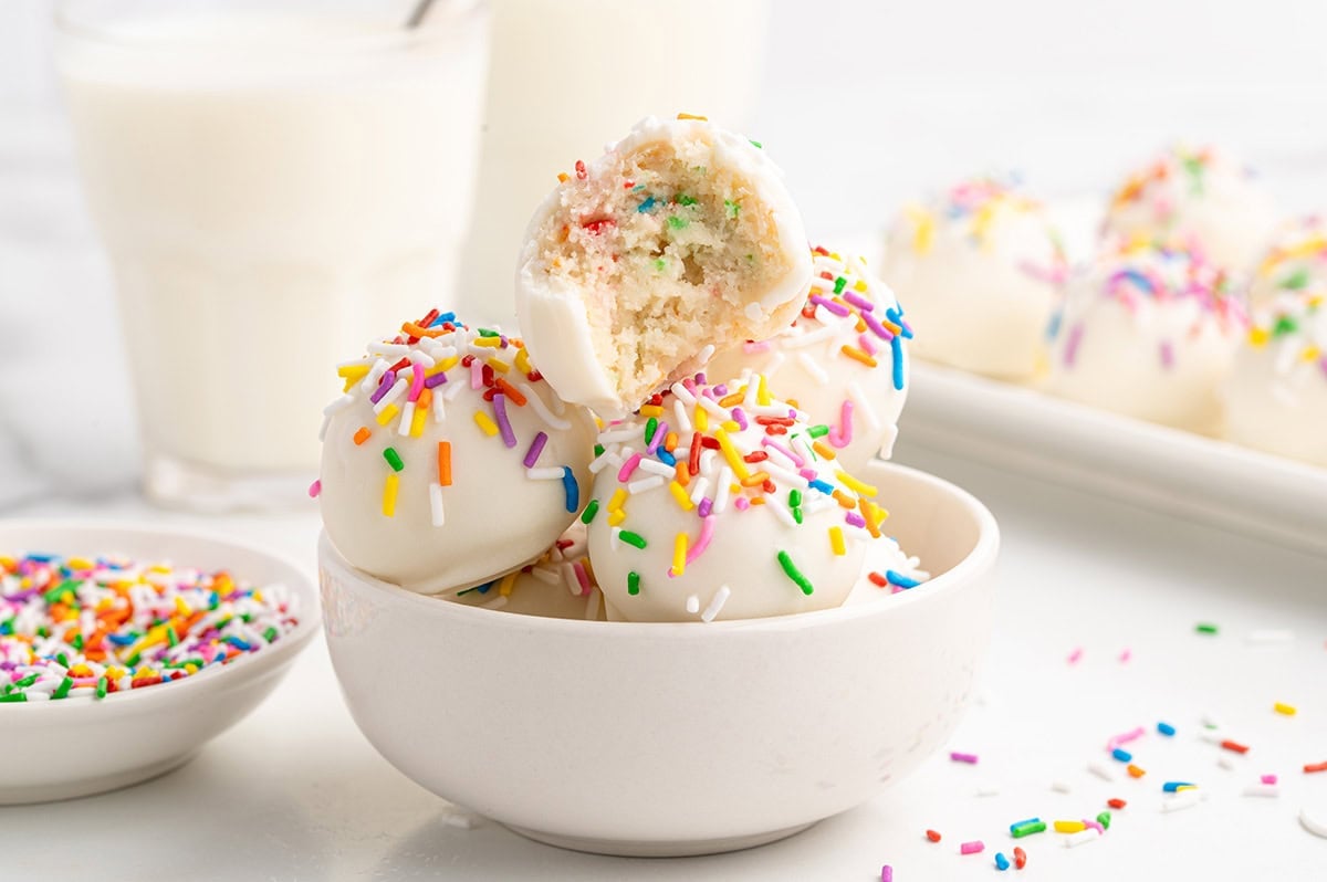 A bowl of white chocolate cheesecake balls with colorful sprinkles on top.