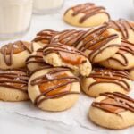 twix thumbprint cookies stacked on top of parchment paper.