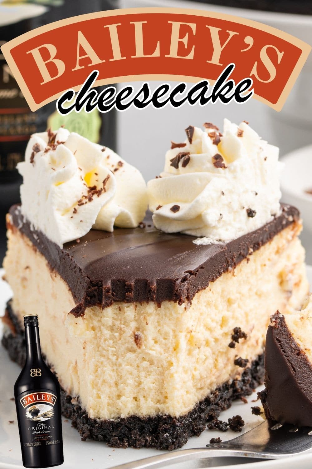 A slice of creamy Baileys Irish Cream cheesecake with a chocolate cookie crust, topped with chocolate ganache and whipped cream served on a white plate