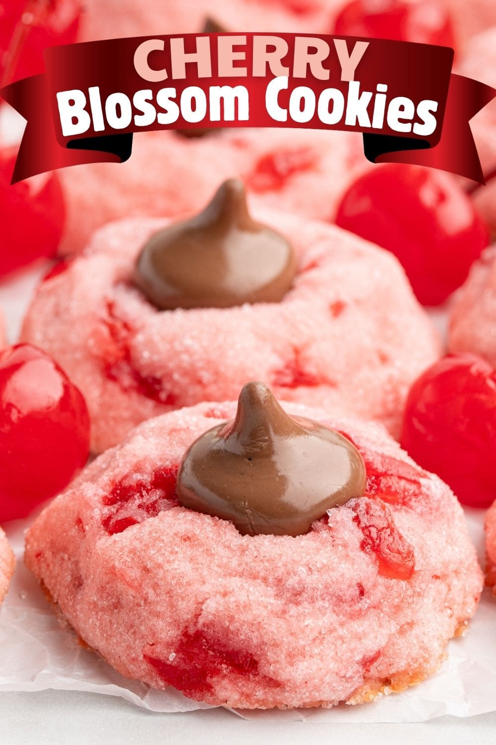 Close up of Chewy Cherry Blossom Cookies with cherries on a parchment paper