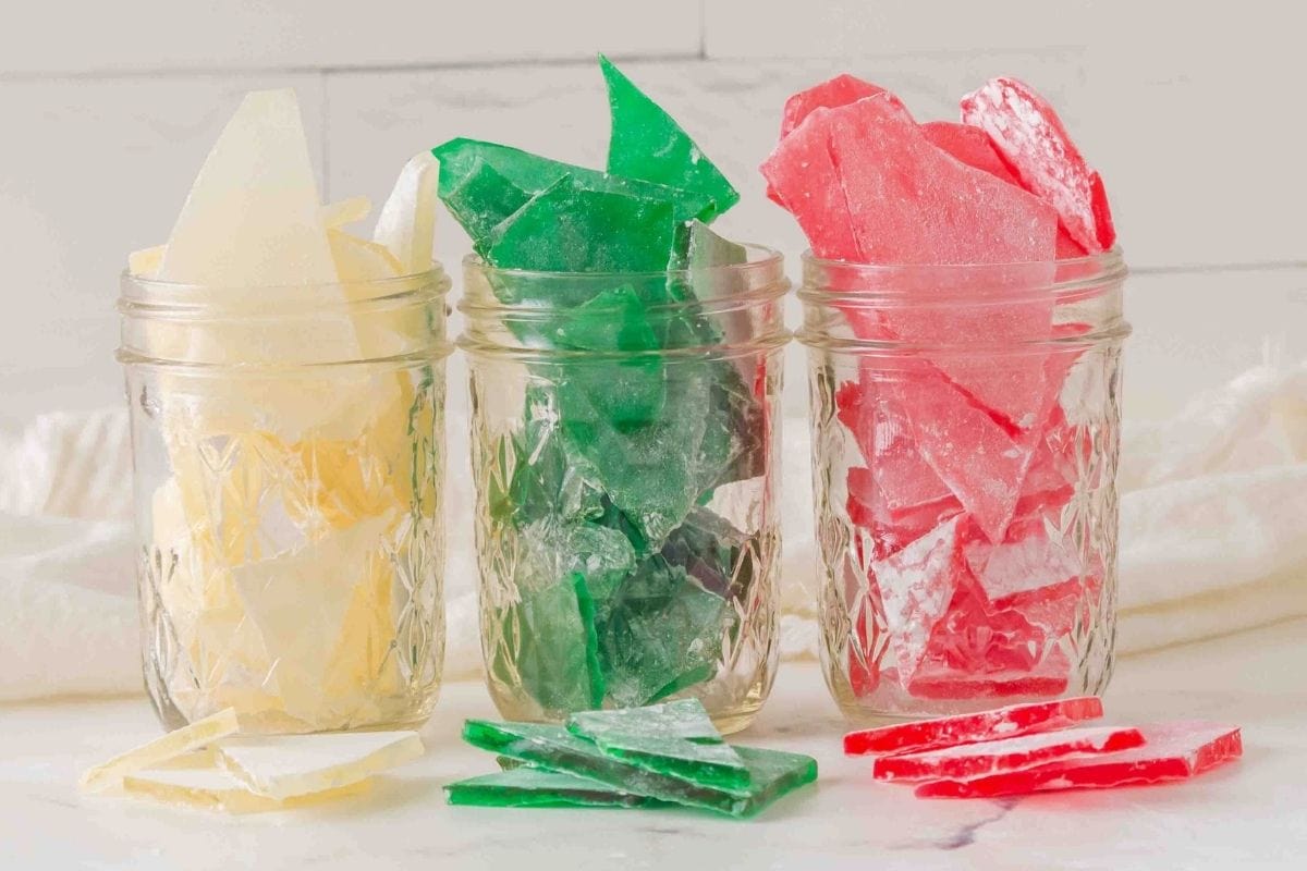 Shards of hard candy sit in glass jars, showing off clear, green, and red hues.