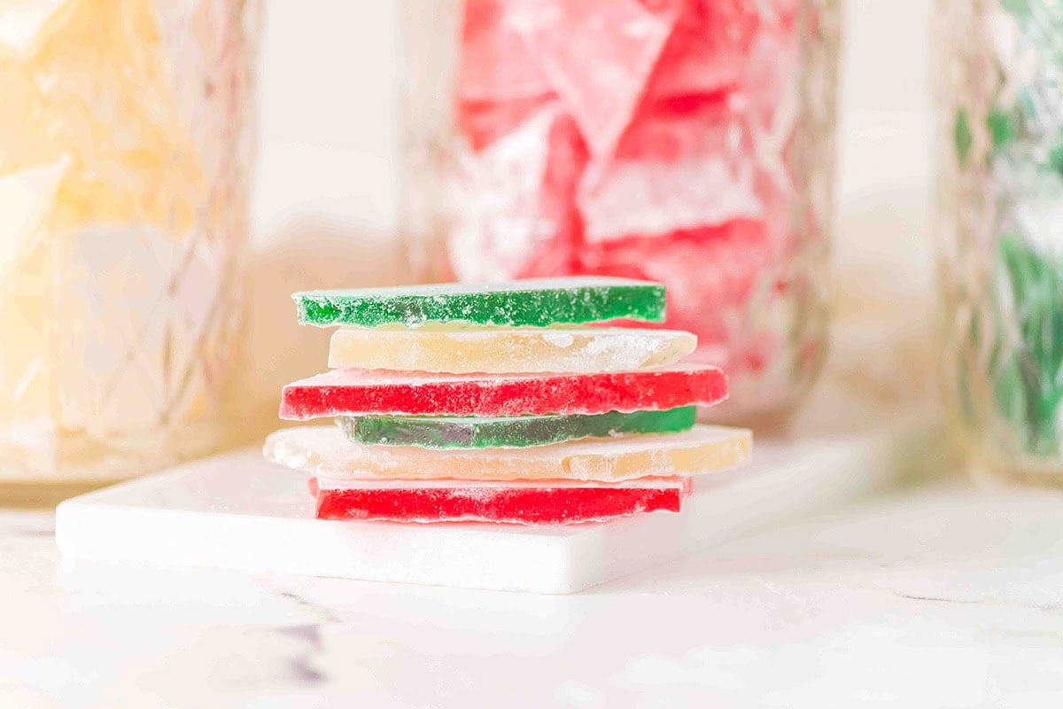 A stack of thin red, green, and yellow hard candy slices rests on a white surface.