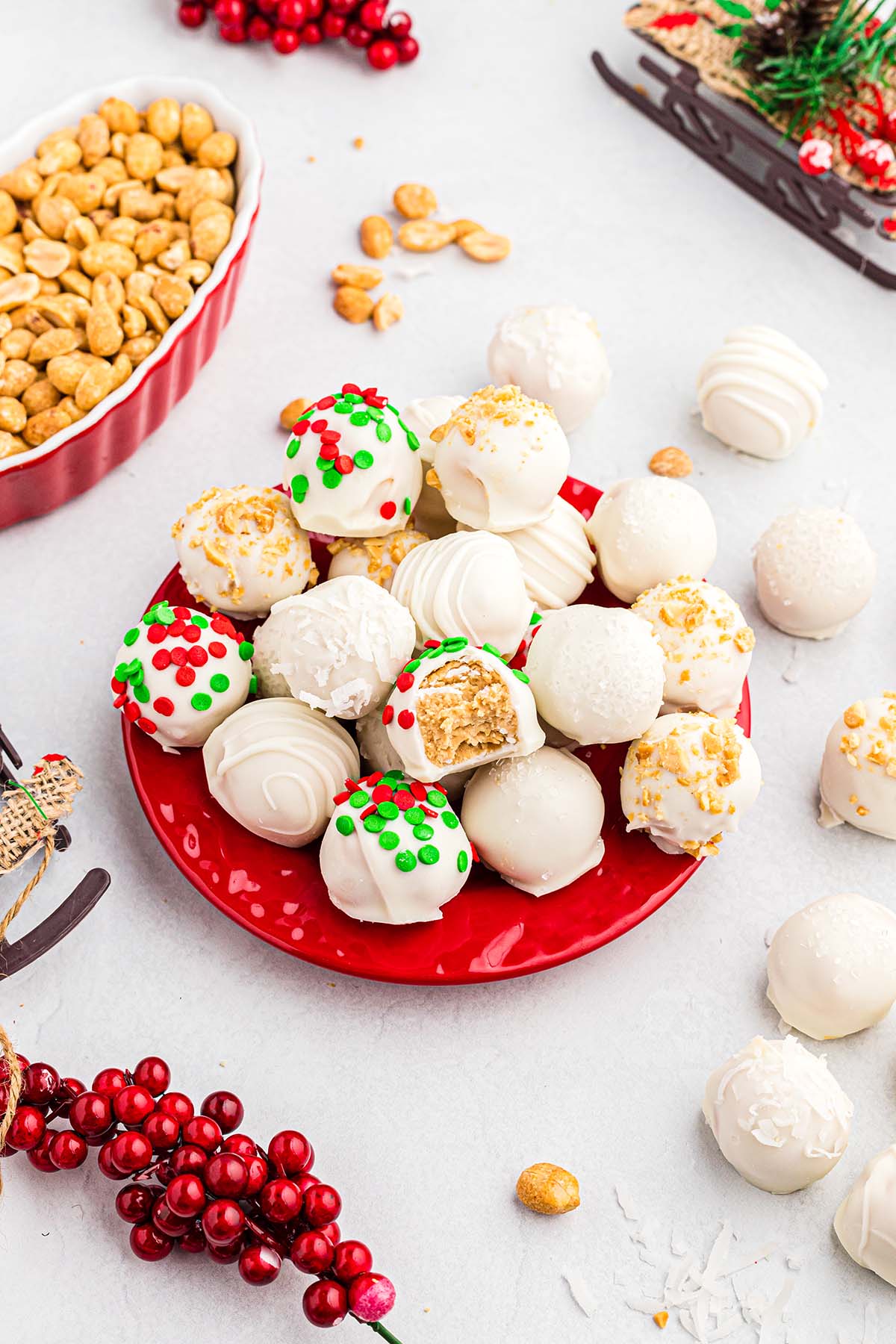 A red plate holds white chocolate truffles topped with red and green sprinkles for Christmas.