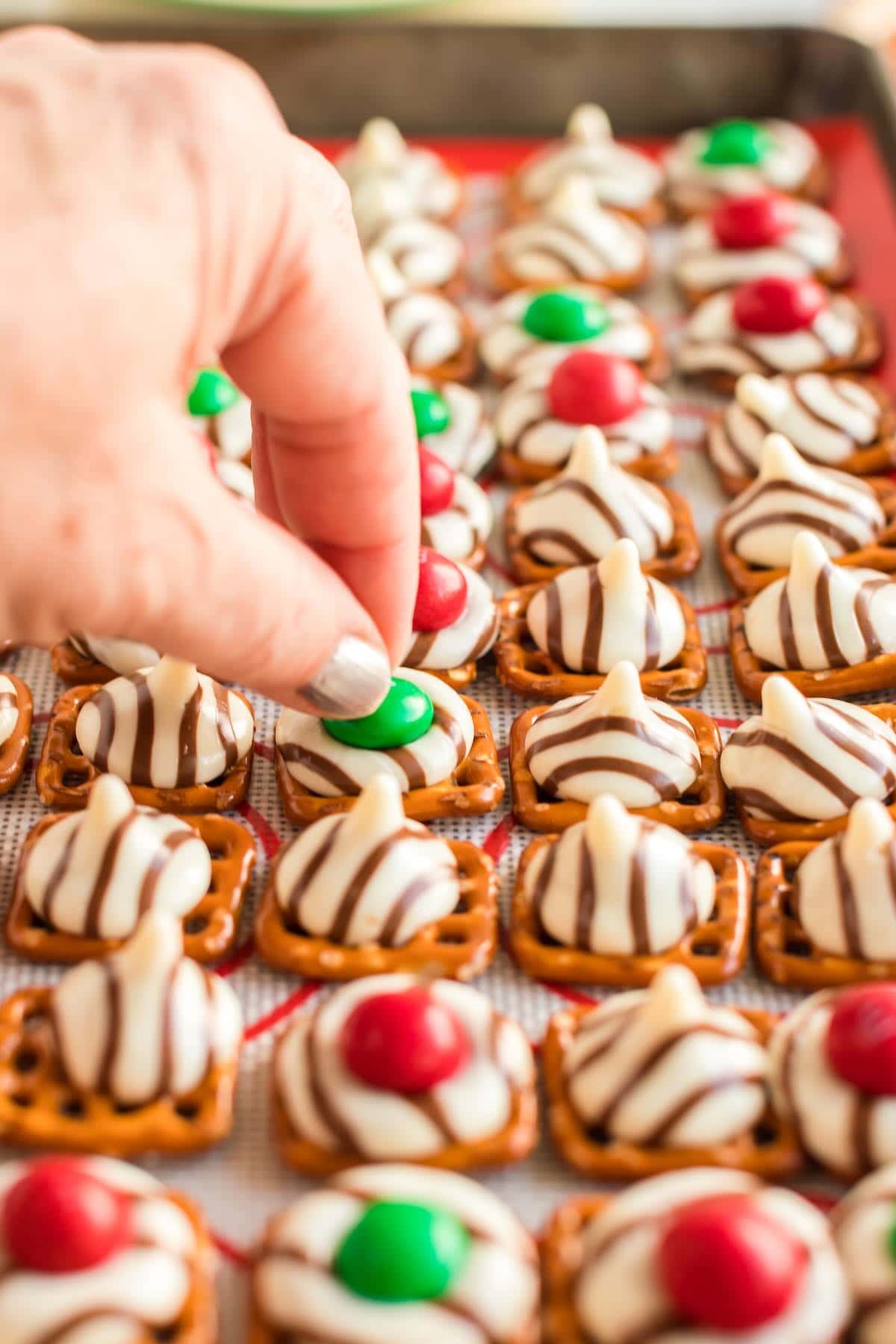 A hand putting a piece of M&M on Pretzel Hugs