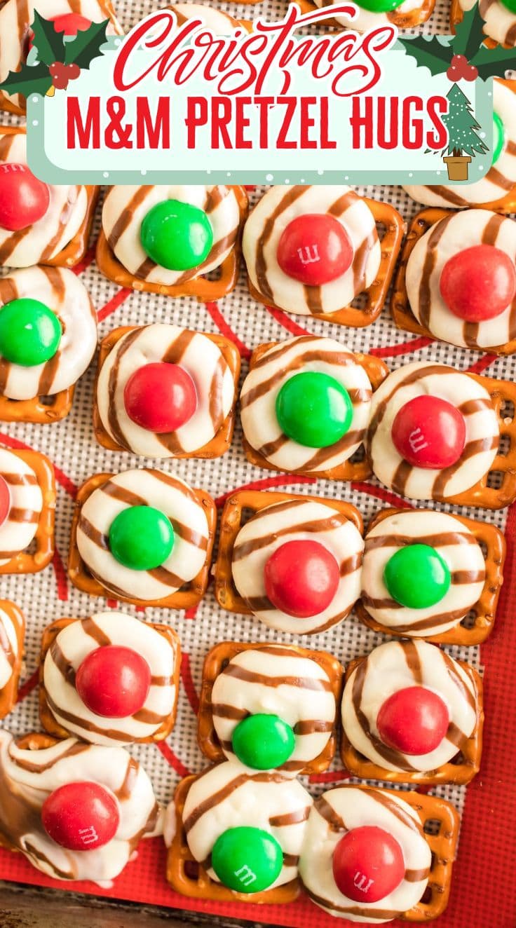 Christmas Pretzel Hugs topped with melted Hershey’s Hugs and red and green M&Ms on a silicone mat