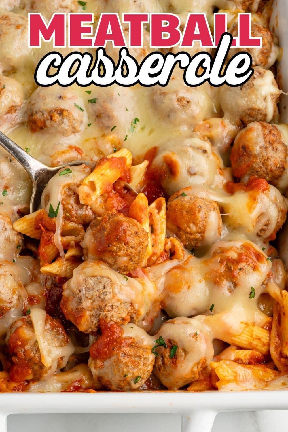 Cheesy meatball casserole close-up with a spoon scooping out pasta and meatballs.