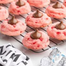Fresh cherry kiss cookies cool on a wire rack, topped with chocolate Hershey's Kisses.