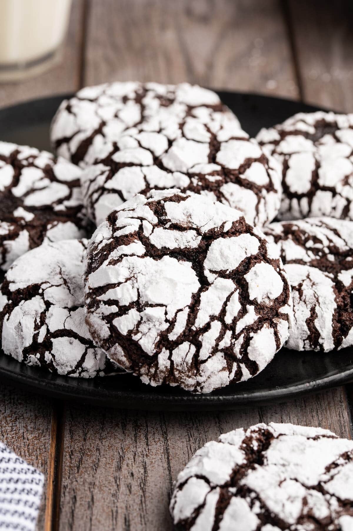 a couple of chocolate crinkle cookies on black plate. 