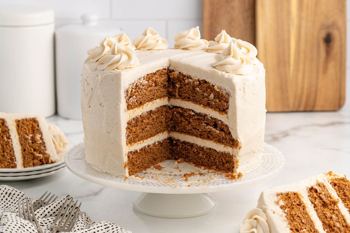 Three-layer gingerbread cake with thick white icing, cut to reveal soft crumb inside.
