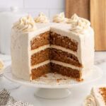 Sliced gingerbread cake shows moist layers topped with creamy white frosting on a cake stand.
