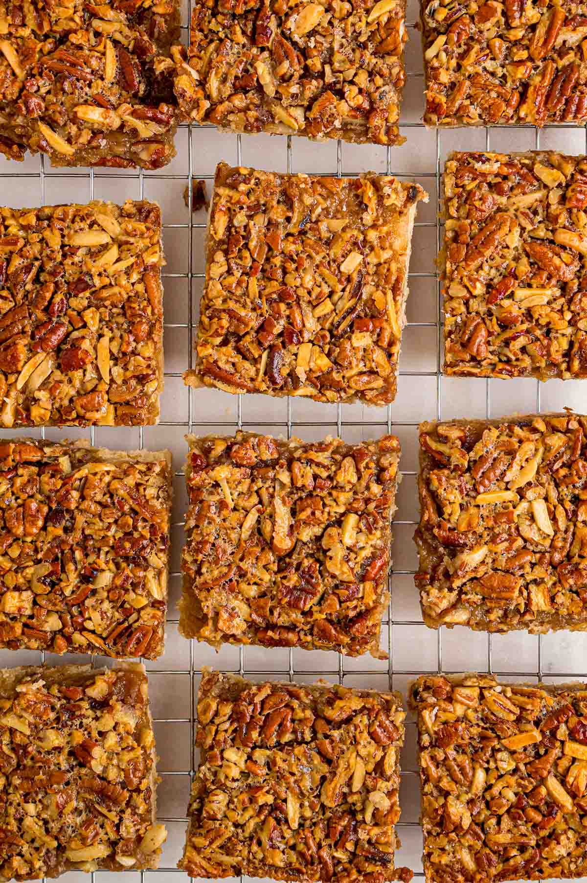 Fresh pecan pie bars cool on a wire rack, topped with crunchy nuts and sticky caramel.