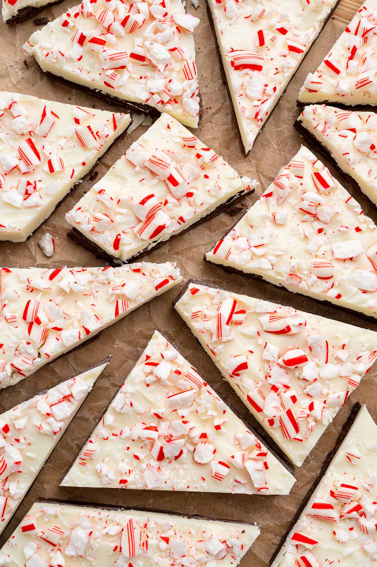 Pieces of white chocolate peppermint bark topped with crushed red and white candy on parchment paper.