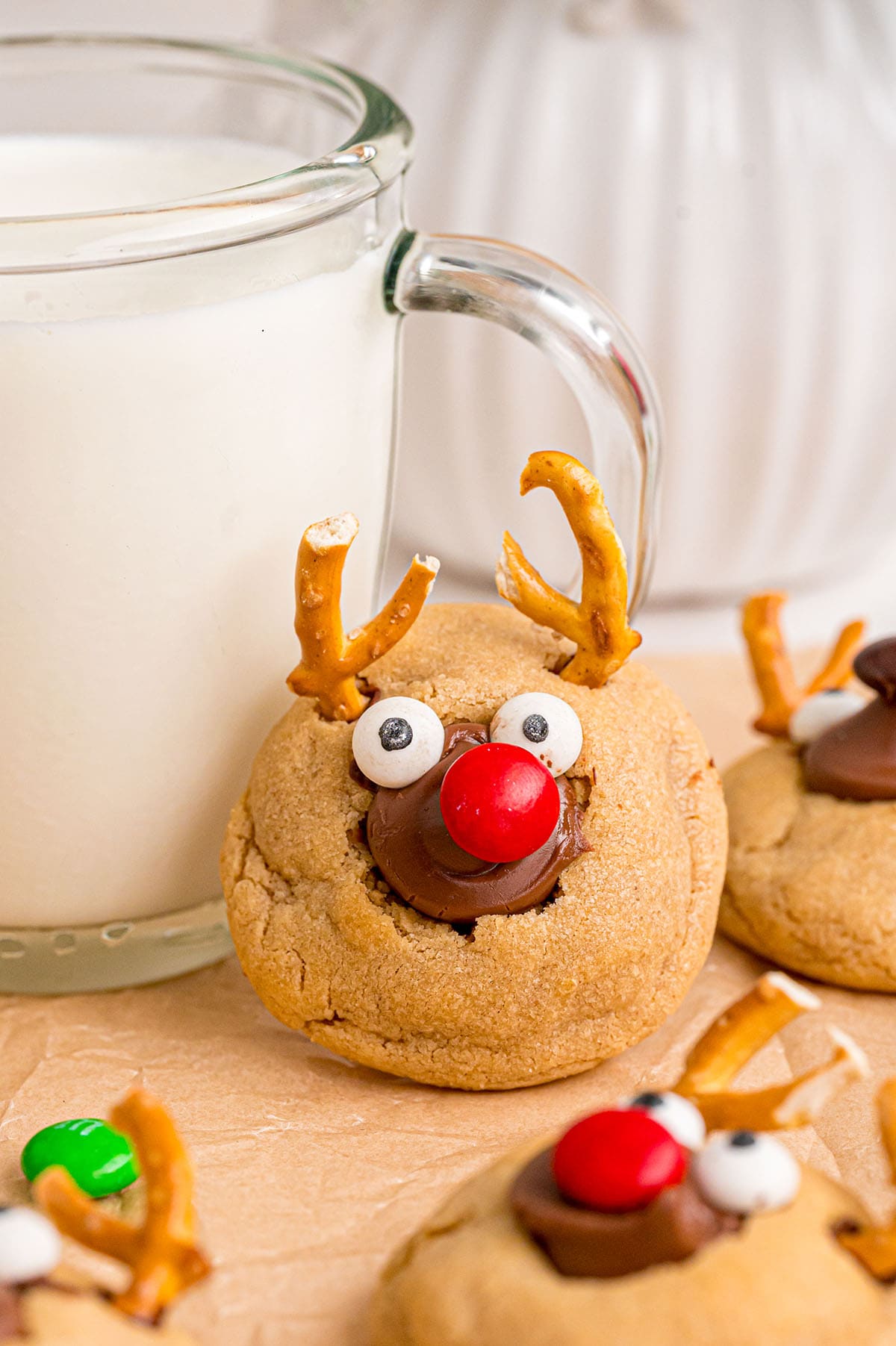 Cute reindeer peanut butter blossom cookies sit next to a glass of milk.