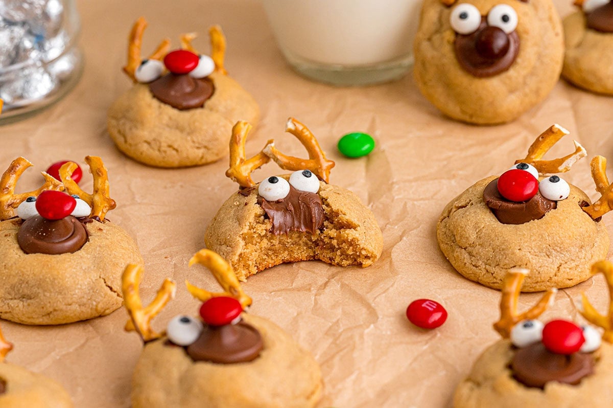 Cute reindeer-shaped cookies feature chocolate kisses, red M&M noses, and googly eyes made from candies.