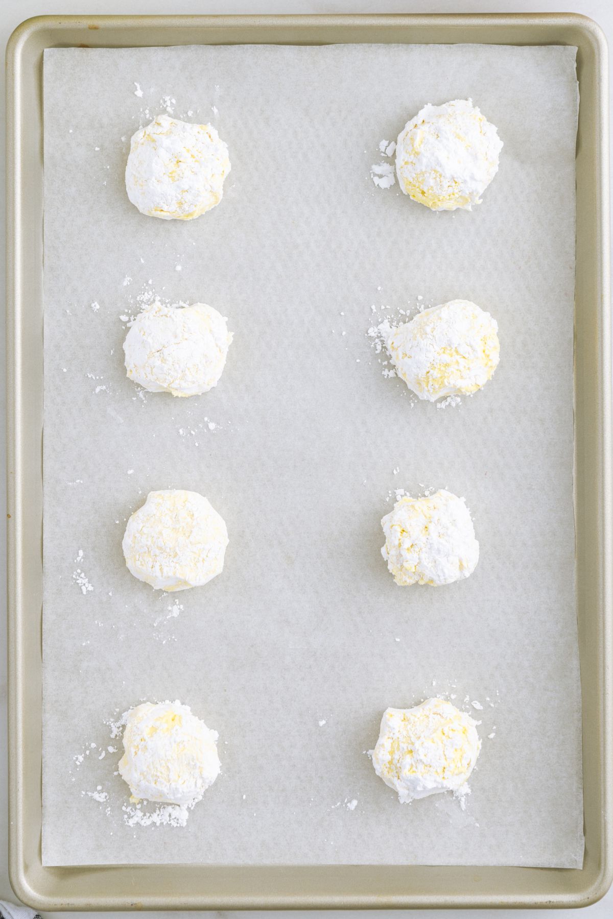 cookie dough covered with powdered sugar placed on top of baking sheet.