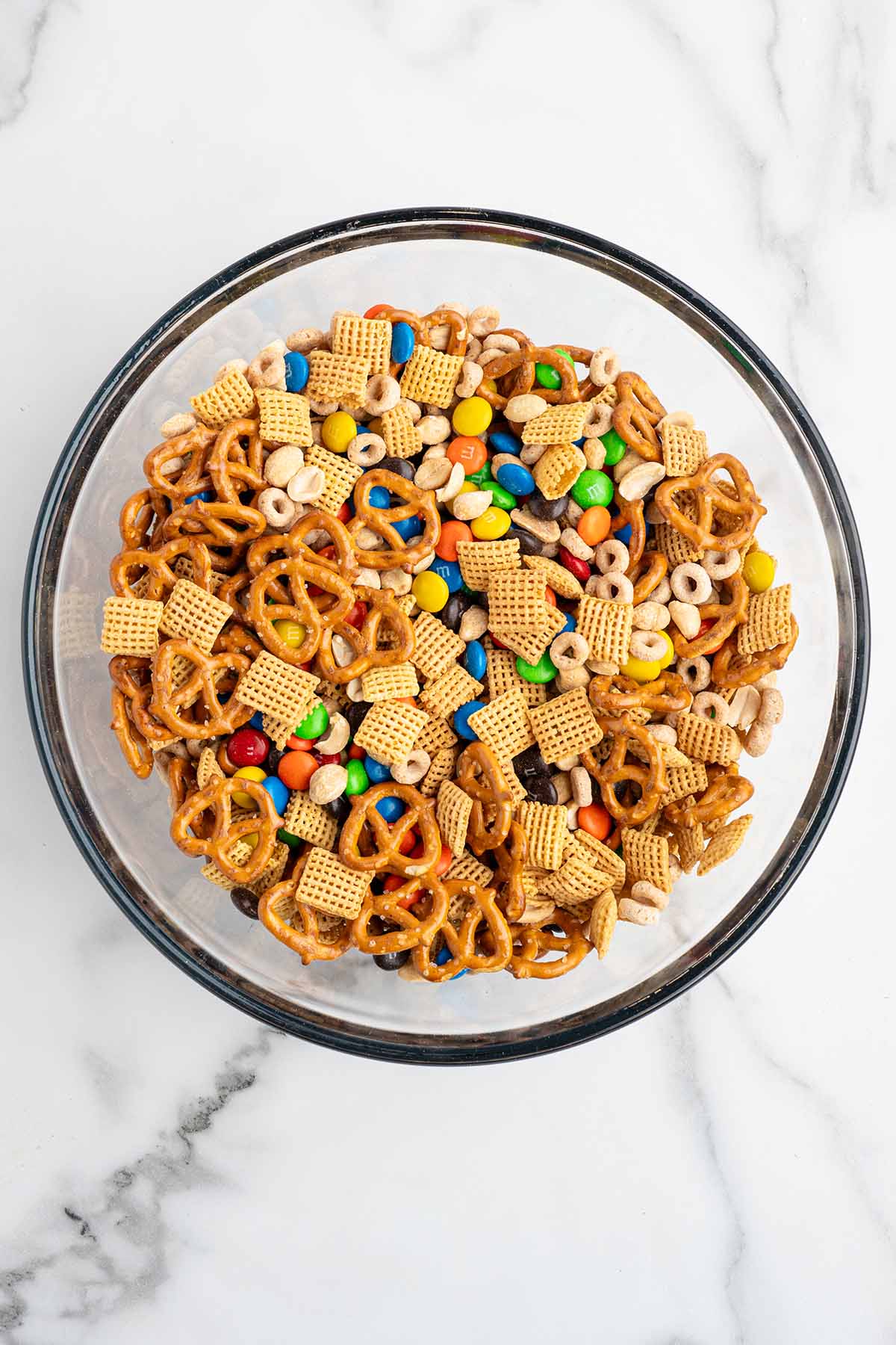 combine Corn CHEX, Cheerios, pretzels, peanuts, and 2 cups of M&M’s