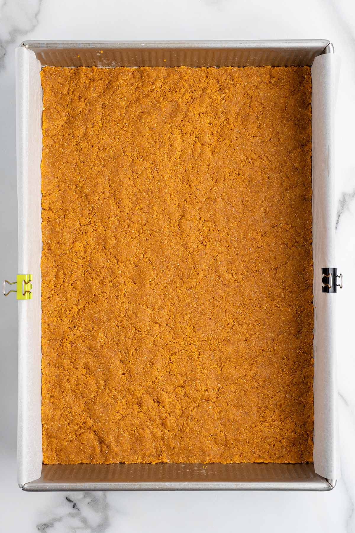 pressing graham crackers crumbs at the bottom of the pan. 
