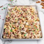 Christmas Chex Mix on a tray with red and green M&Ms, pretzels, and white chocolate bits.