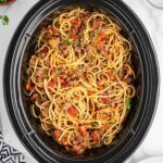 Crockpot taco spaghetti with ground beef and tomato sauce, topped with fresh herbs.