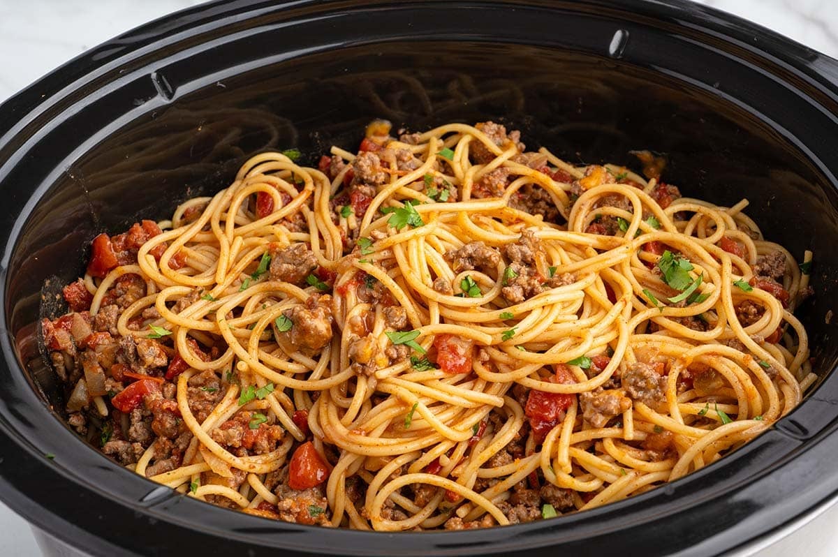 Crockpot taco spaghetti with ground beef, tomatoes, and cilantro on top.