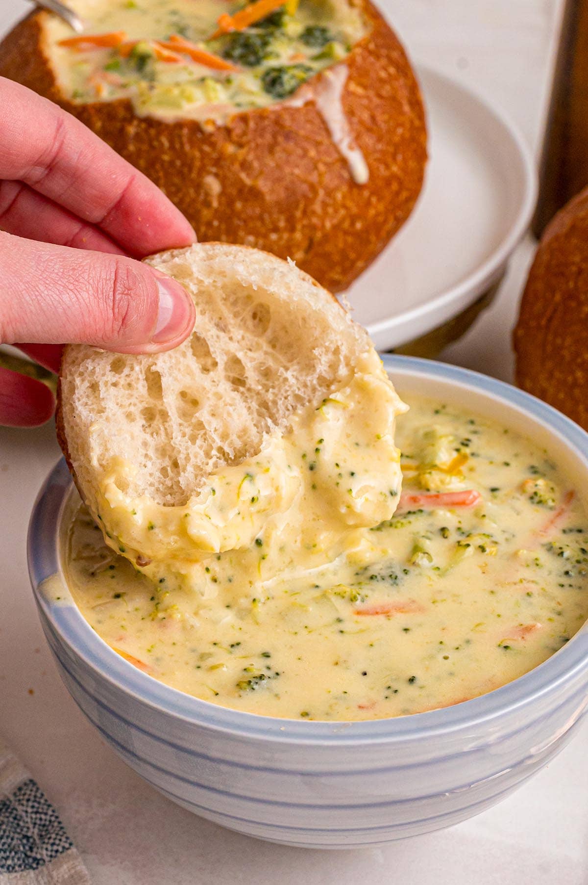 Hand pulls bread from Panera broccoli cheddar soup in a bread bowl.