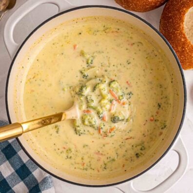Ladle scoops creamy Panera broccoli cheddar soup with broccoli and carrots.