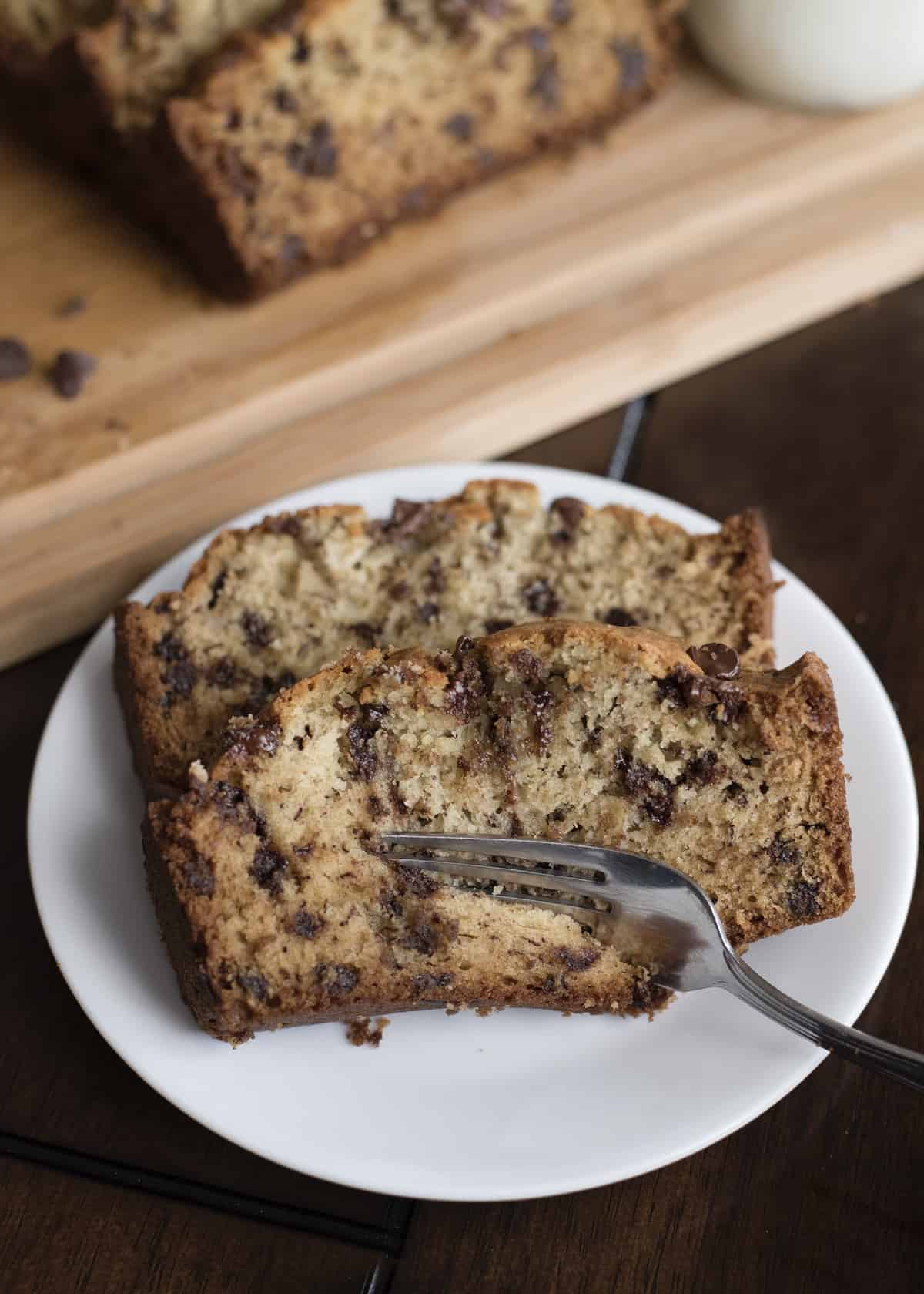 Two slices of chocolate chip banana bread on a white plate with a fork.