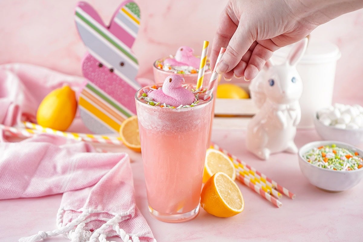 Pink Easter punch in a tall glass topped with Peeps chicks and lemon slices.