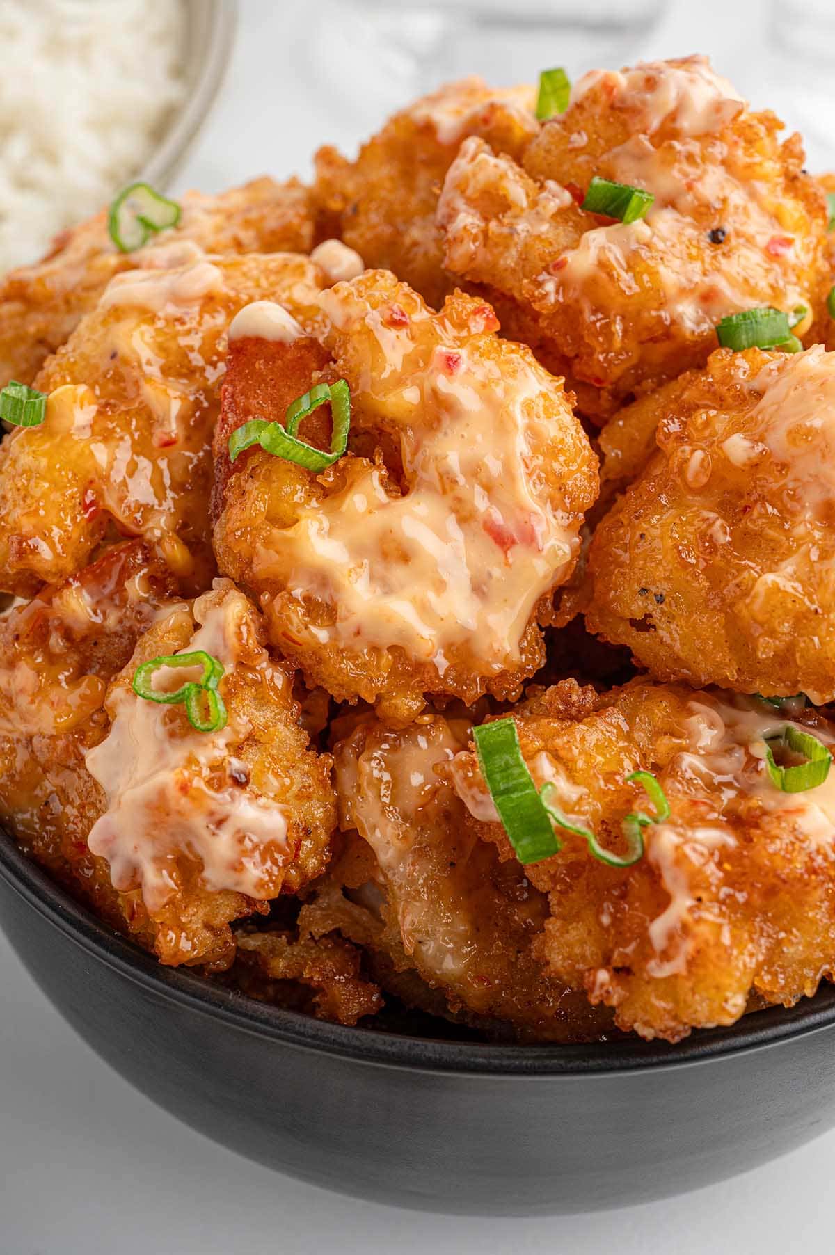 Crispy Bang Bang shrimp coated in creamy spicy sauce with green onions.