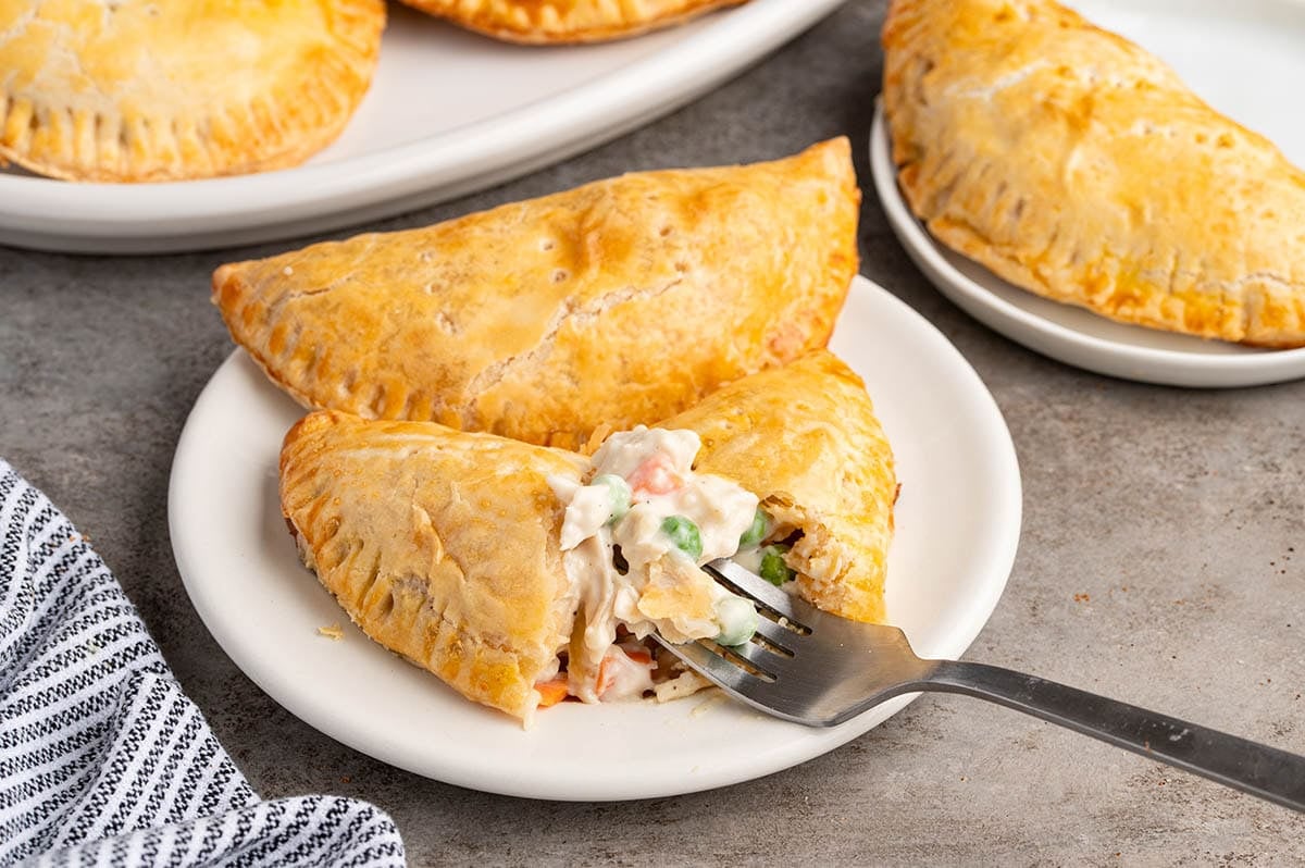 Golden chicken pot pie hand pies on a white plate.