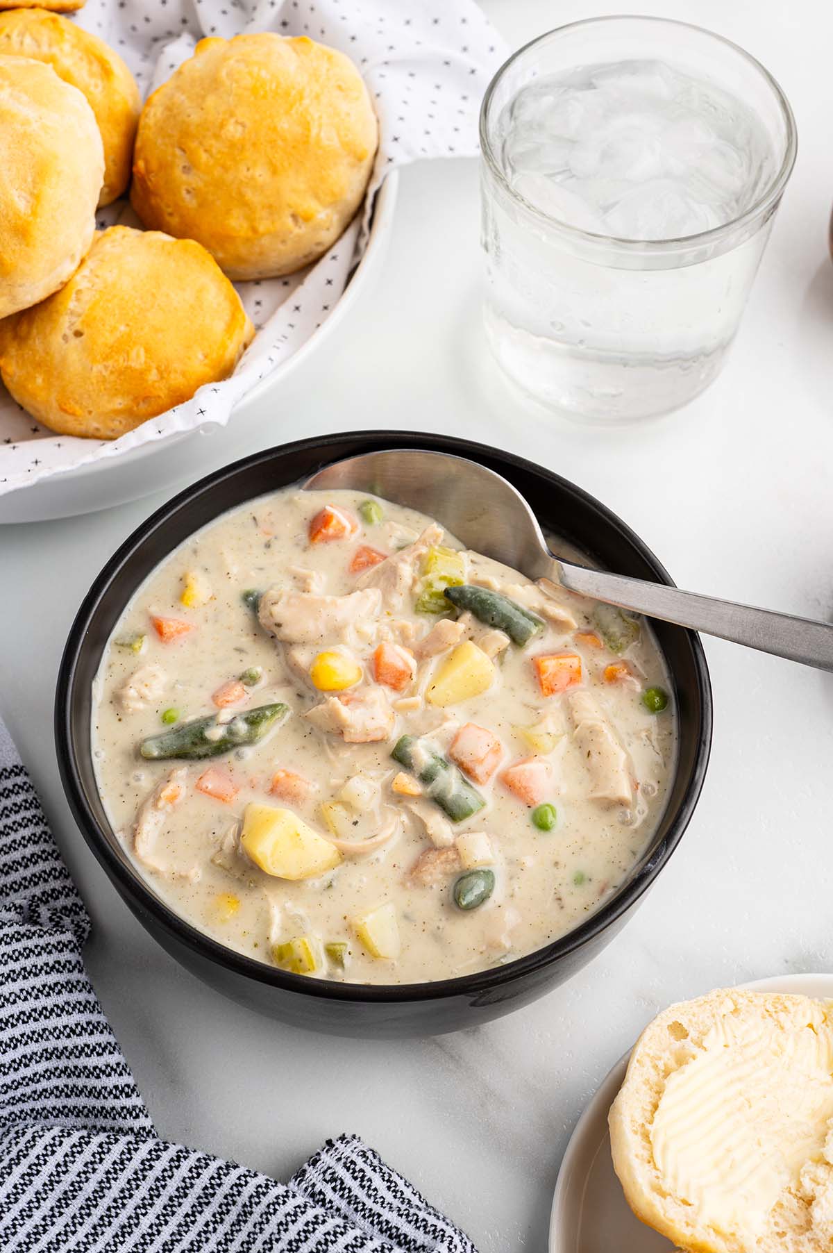 Bowl of creamy chicken pot pie soup with chicken, carrots, potatoes, corn, green beans, and peas.