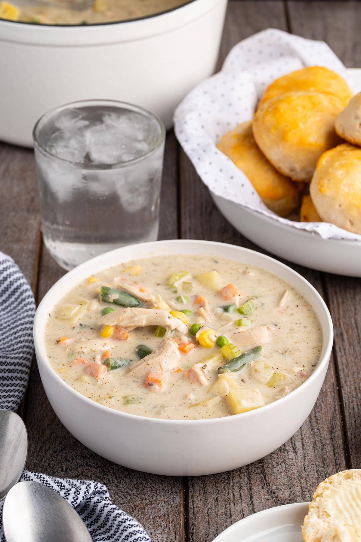 Bowl of creamy chicken pot pie soup with chicken, potatoes, carrots, green beans, and corn.