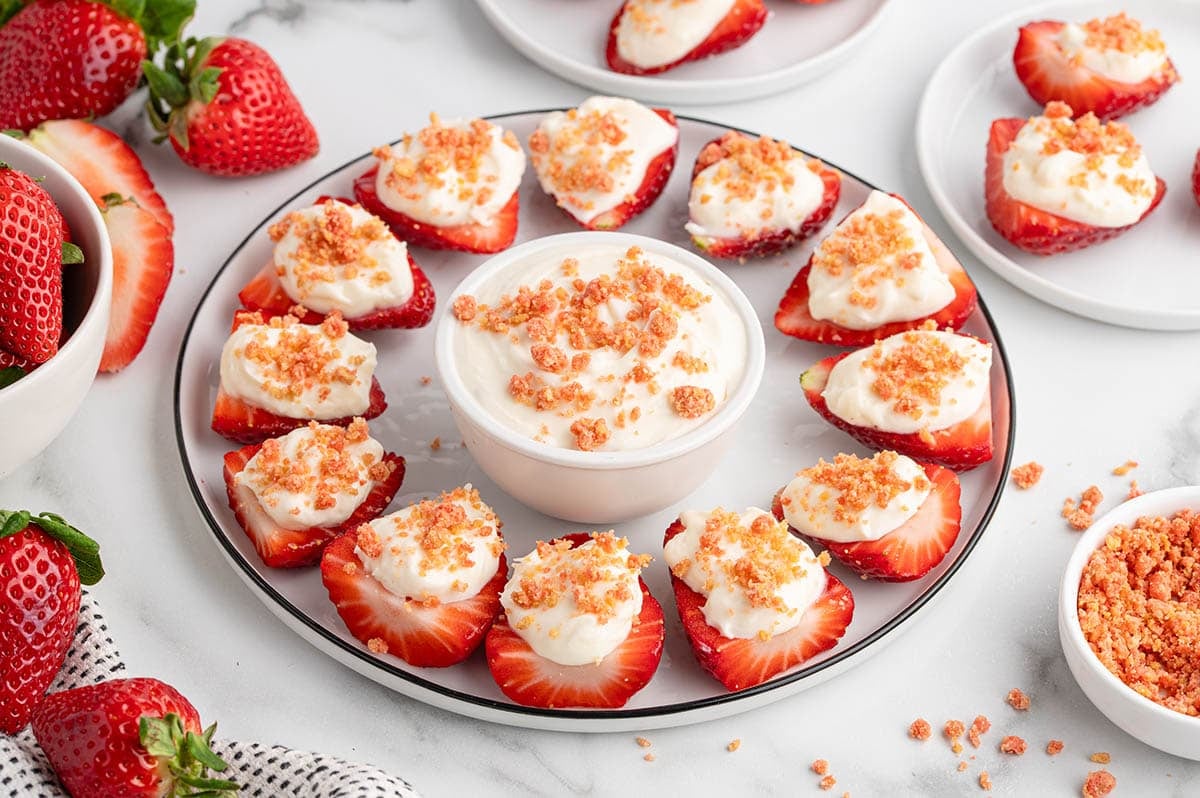 Deviled strawberries filled with cream and topped with crumbs on a plate.