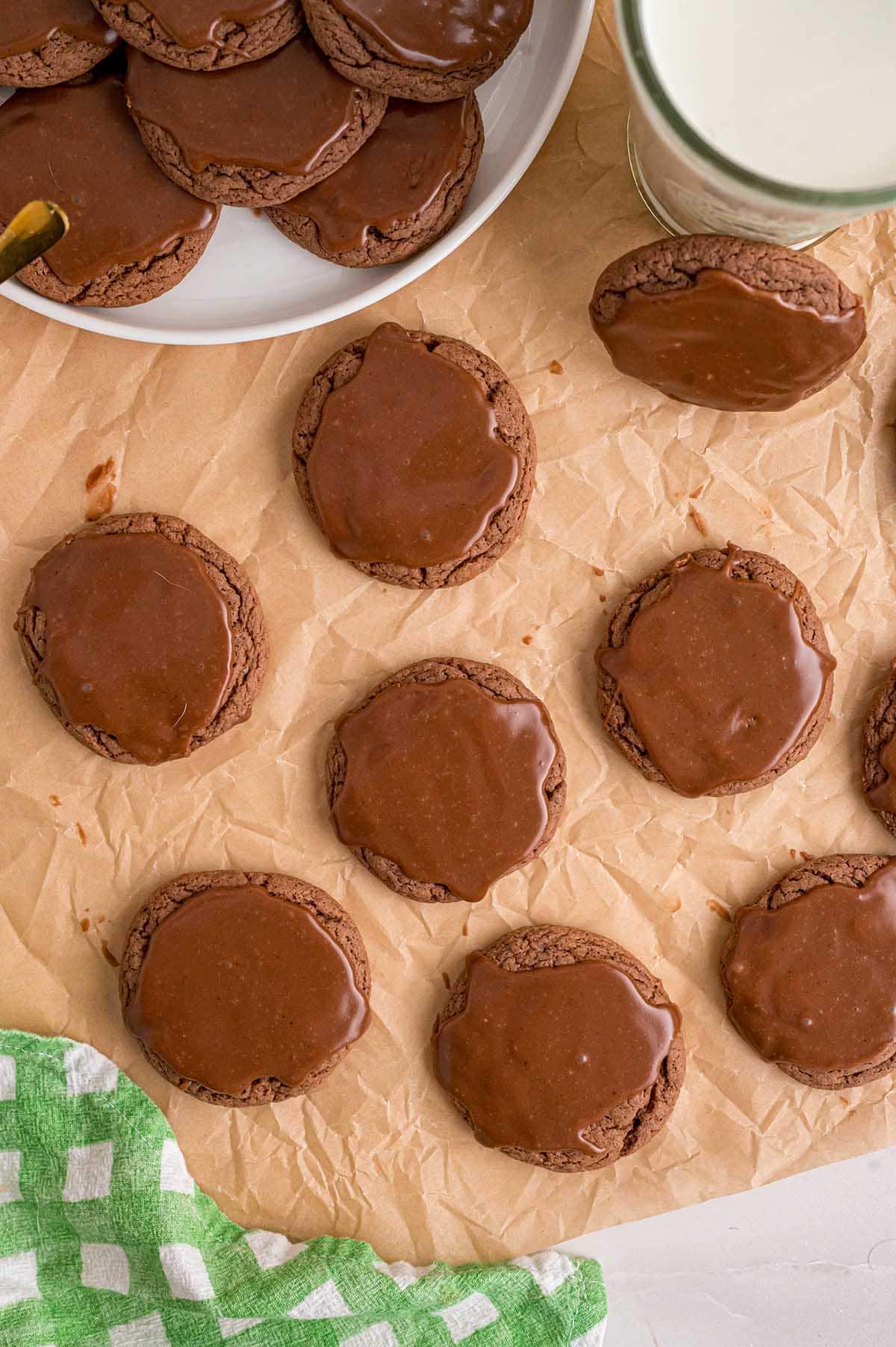 Fresh Texas sheet cake cookies topped in chocolate next to a tall milk glass.
