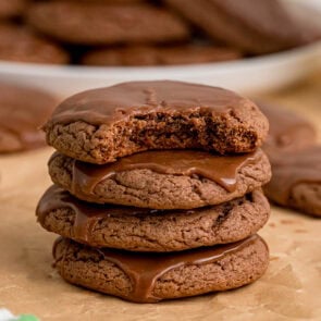 Texas sheet cake cookies stacked high, glazed in chocolate, one bitten on top.