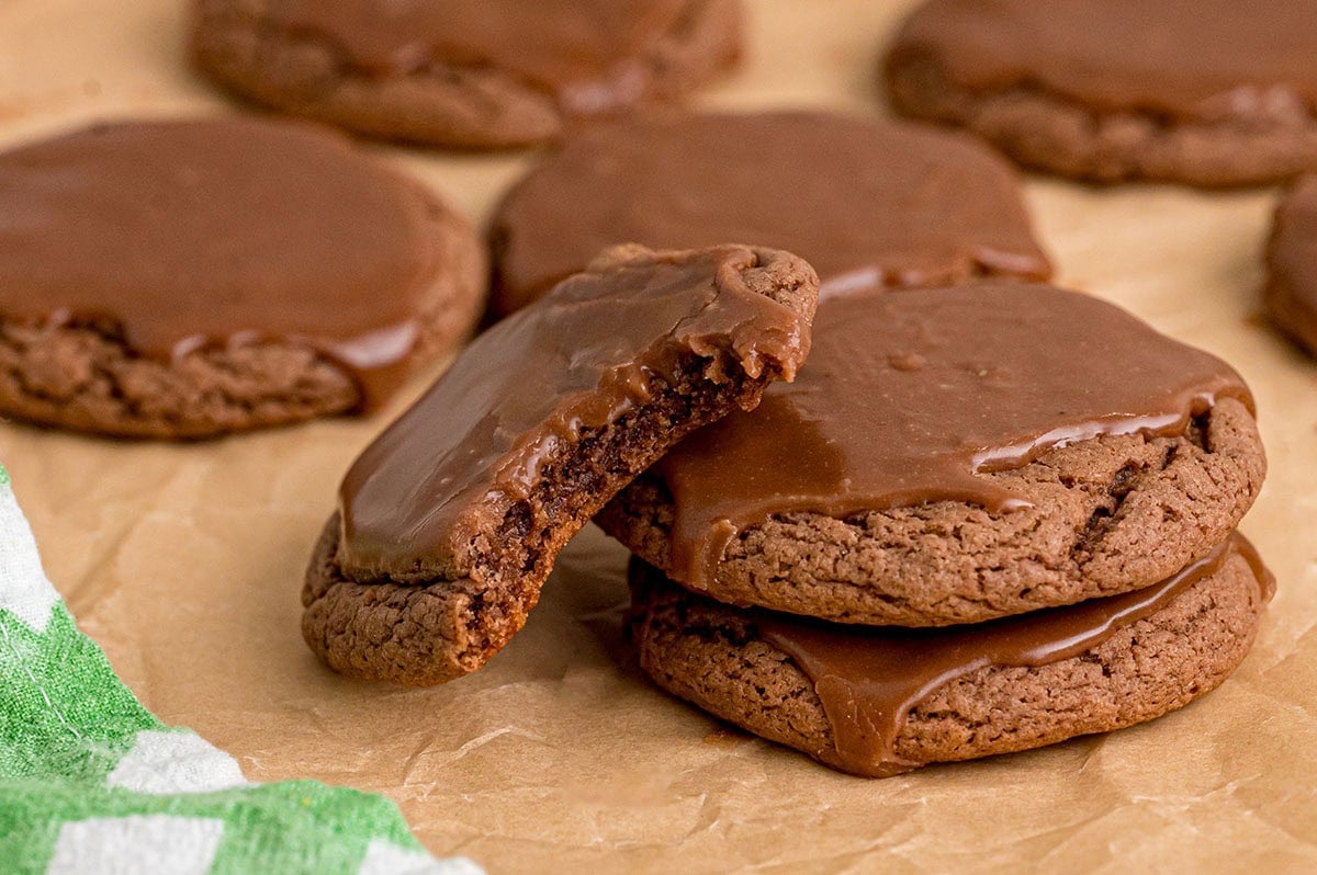 Texas sheet cake cookies with thick chocolate glaze and one bitten in half.