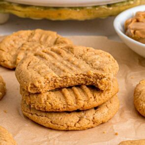 3 ingredient peanut butter cookies stacked on top of parchment paper.